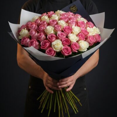 Bouquet "Duo de Roses" ​L'Esprit de la Création ​Un hommage intemporel à la reine des fleurs. Ce bouquet généreux mise sur l’élégance d’un bicolore doux et romantique : le contraste entre la pureté du blanc et l’éclat du rose. Son allure ronde et opulente en fait le messager idéal pour toutes les occasions, de la déclaration d’amour aux remerciements les plus sincères. ​Détails de la Composition ​Un bouquet sur mesure où chaque rose est sélectionnée pour la beauté de son bouton : ​Harmonie de Couleurs : Une répartition soignée avec deux tiers de roses roses pour la tendresse et un tiers de roses blanches pour la lumière. ​Personnalisation : Le volume du bouquet est adaptable selon vos envies. Nous répartissons harmonieusement les couleurs en respectant cet équilibre, quel que soit le nombre de tiges choisi. ​Écrin de Présentation : Le bouquet est magnifié par un double emballage contrasté qui souligne l’intensité des couleurs florales. ​Le Conseil de l'Artisan ​"La rose est une fleur noble qui s’épanouit jour après jour. Pour profiter de ce bouquet le plus longtemps possible, placez-le dans un vase propre avec un grand volume d'eau. Un léger biseau au bas des tiges tous les deux jours permettra une hydratation optimale de chaque bouton."